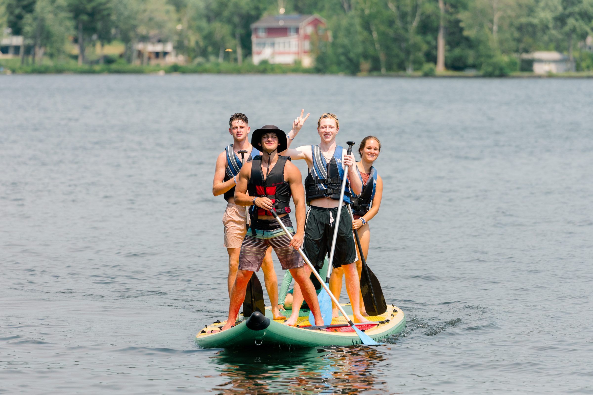 Camp Winadu staff riding a giant paddleboard on the lake