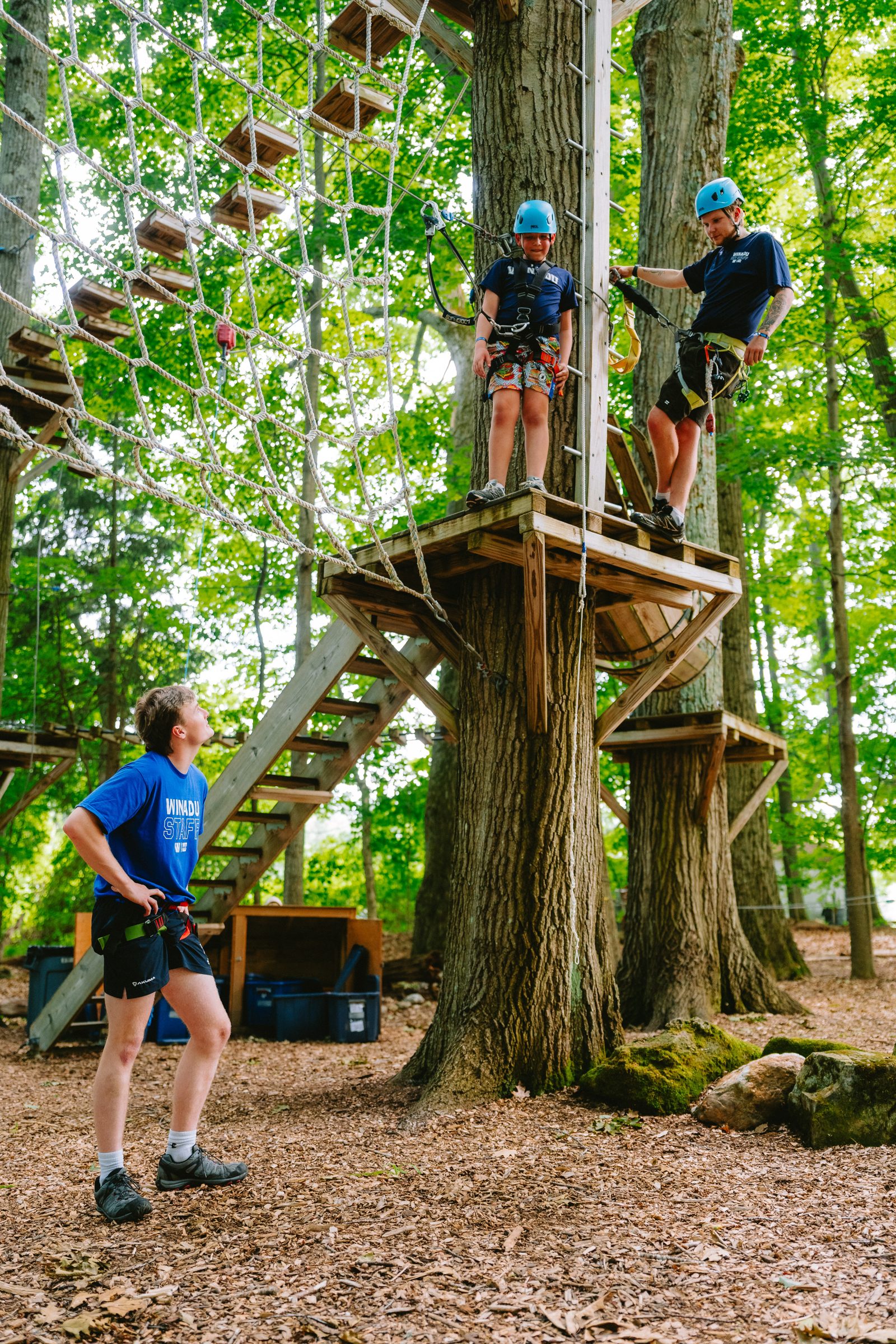 Camp Winadu staff and a camper on the aerial adventure course platforms