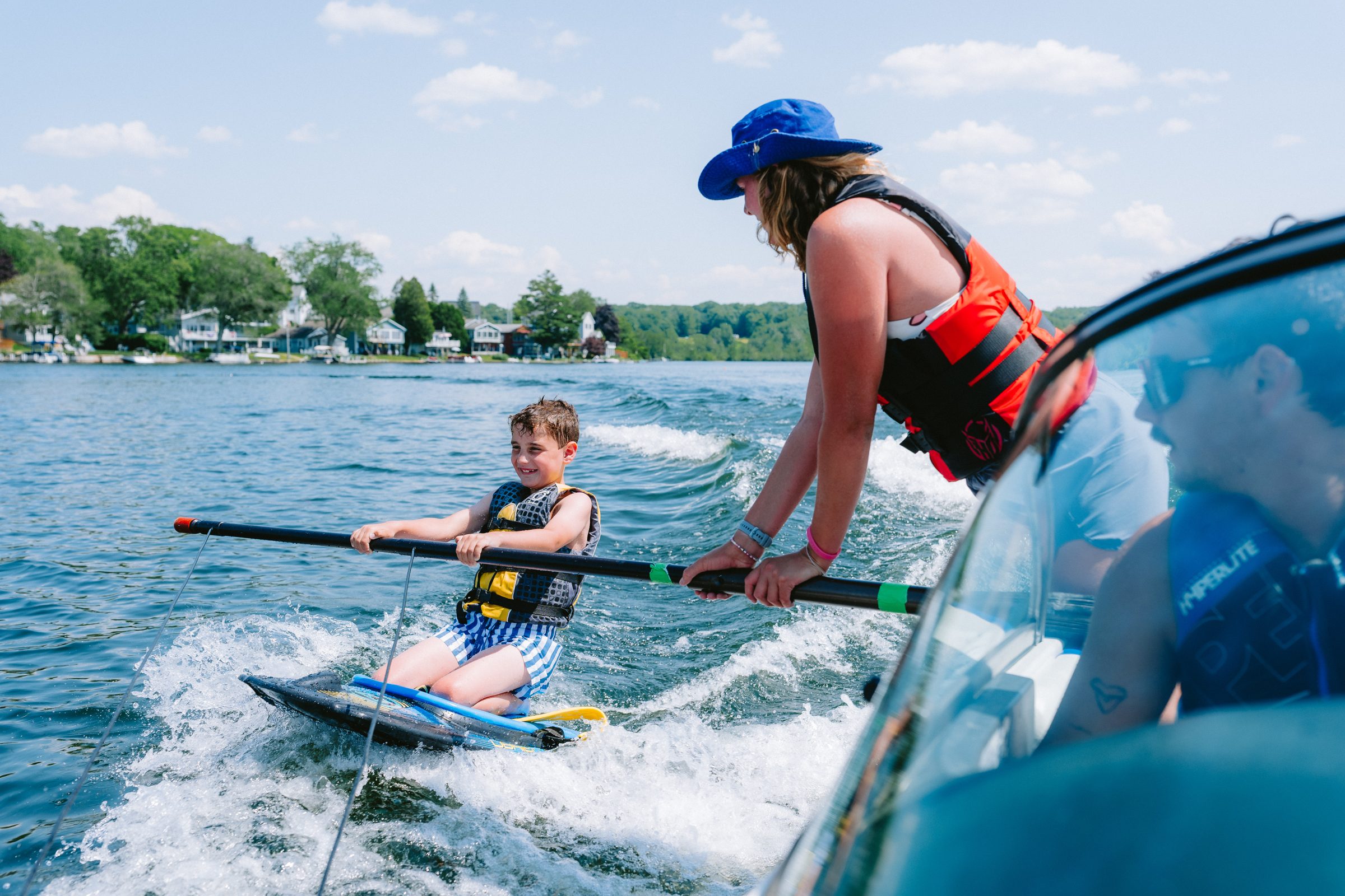 Camp Winadu waterski instructor helping a young camper up on a kneeboard